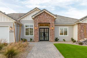 Property entrance featuring board and batten siding, french doors, brick siding, and an attached garage