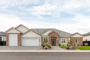 View of front of home featuring board and batten siding, a garage, decorative driveway, and brick siding