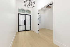 Foyer entrance with a high ceiling, light wood-style flooring, a chandelier, and recessed lighting