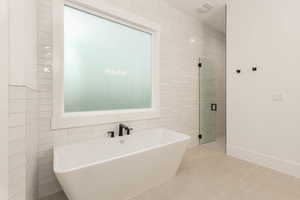 Bathroom with tile walls, a freestanding bath, light tile patterned floors, and a shower stall