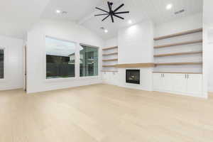Unfurnished living room featuring light wood finished floors, ceiling fan, a fireplace, recessed lighting, and built in features