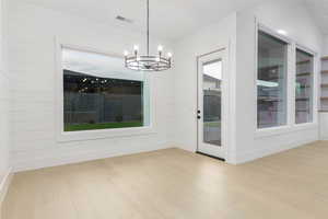 Unfurnished dining area with light wood-style flooring and a chandelier