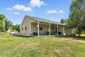 Rear view of property with a patio, a lawn, and a ceiling fan