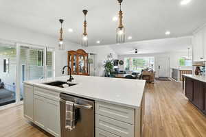 Kitchen featuring dishwasher, white cabinetry, pendant lighting, ceiling fan, and light wood finished floors