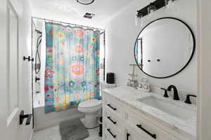 Full bathroom with shower / tub combo with curtain, vanity, light tile patterned floors, and a textured ceiling