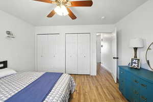 Bedroom featuring two closets, light wood-style flooring, and ceiling fan
