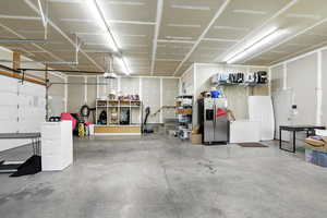 Garage featuring stainless steel fridge with ice dispenser and white refrigerator
