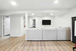 Living area with light wood-style floors and recessed lighting