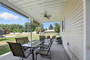View of patio with outdoor dining area, a trampoline, a ceiling fan, and an outdoor structure