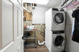 Laundry room with stacked washer / dryer and wood finished floors