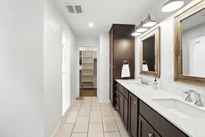 Full bath with double vanity, a walk in closet, backsplash, recessed lighting, and light tile patterned floors