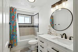 Bathroom featuring shower / bath combination with curtain, vanity, and light tile patterned floors