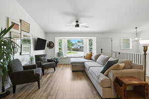 Living room featuring light wood-style flooring, a chandelier, and a ceiling fan