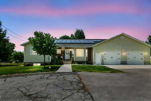 Ranch-style home featuring solar panels, a yard, covered porch, concrete driveway, and a garage
