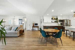 Dining room with a chandelier, lofted ceiling, light wood-style floors, and recessed lighting