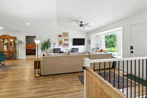 Living room featuring lofted ceiling, light wood-style flooring, and a ceiling fan