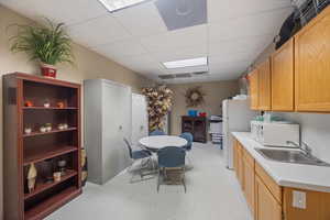 Kitchen featuring light flooring, a paneled ceiling, light countertops, white appliances, and light brown cabinets
