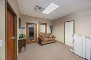 Living room featuring a paneled ceiling and carpet flooring