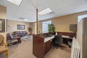 Office featuring radiator heating unit and a paneled ceiling
