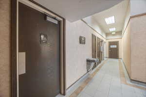 Hallway with light tile patterned flooring and a textured wall