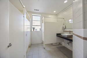 Full bath with vanity, light tile patterned flooring, a stall shower, and tile walls
