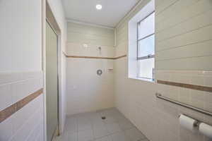 Full bathroom with tile walls, a stall shower, and light tile patterned flooring