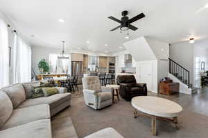 Living area featuring stairway, light wood-style flooring, a ceiling fan, recessed lighting, and a chandelier