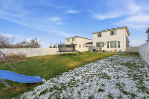 Back of property featuring a trampoline, a playground, and a fenced backyard