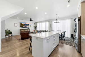 Kitchen featuring a kitchen bar, white cabinetry, pendant lighting, a center island, and recessed lighting