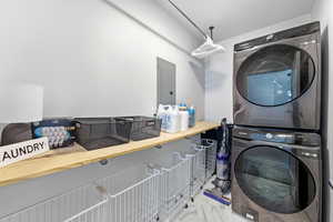 Laundry area with electric panel and stacked washing machine and dryer