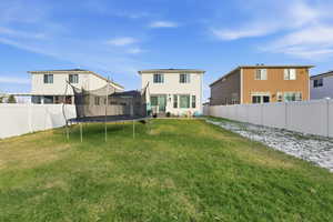 Rear view of house featuring a trampoline and a fenced backyard