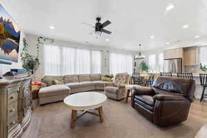 Living area featuring light wood finished floors, healthy amount of natural light, and a ceiling fan
