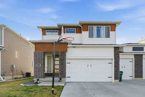 View of front facade featuring driveway, stone siding, a garage, and a front yard