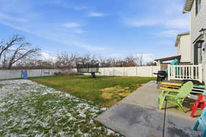 Fenced backyard featuring a trampoline and a playground