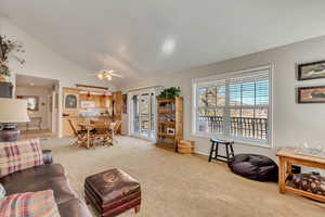 Living area featuring light colored carpet, ceiling fan, and high vaulted ceiling