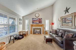 Living area featuring lofted ceiling, carpet flooring, and a tile fireplace