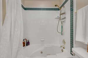Bathroom featuring a combined bath / shower with jetted tub and toilet