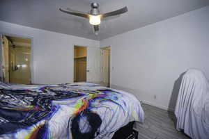 Bedroom with a ceiling fan, a spacious closet, wood finish floors, and ensuite bathroom