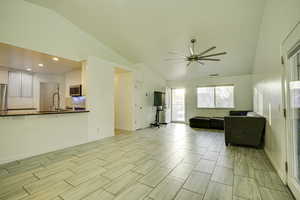 Living area featuring vaulted ceiling, a ceiling fan, recessed lighting, and wood tiled floors