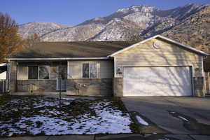 Ranch-style home with brick siding, concrete driveway, a mountain view, and an attached garage