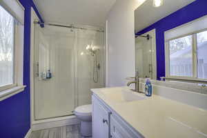 Full bathroom with a stall shower, vanity, a textured ceiling, and wood finish floors