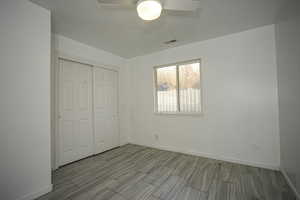 Unfurnished bedroom with a closet, ceiling fan, and wood finish floors