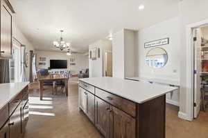 Kitchen featuring dark brown cabinets, a kitchen island, decorative light fixtures, dark wood-style flooring, and recessed lighting
