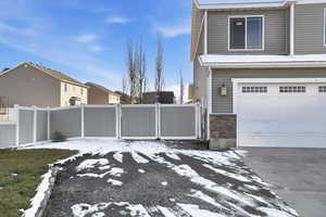View of side of property with stone siding, a garage, a residential view, and concrete driveway
