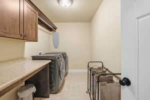 Washroom with washer and clothes dryer, cabinet space, and a textured ceiling