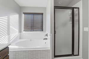 Bathroom with a bath, vanity, and a stall shower