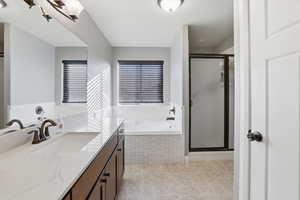 Bathroom with vanity, a bath, and a stall shower