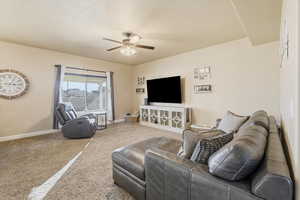 Carpeted living area featuring baseboards and a ceiling fan