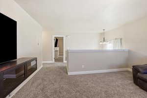 Unfurnished living room featuring light carpet and a chandelier