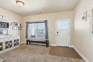Foyer with light colored carpet and light wood-type flooring